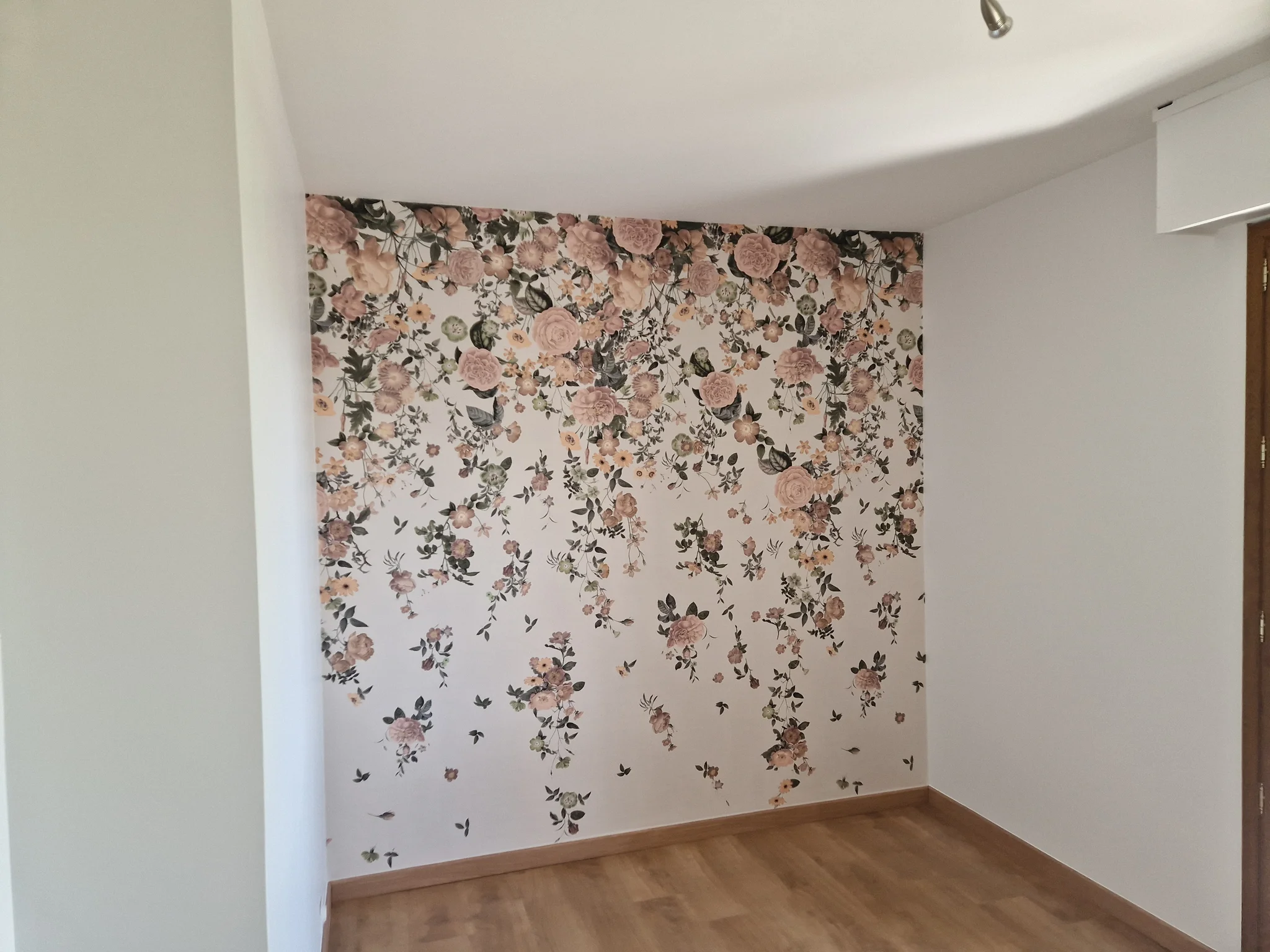 Papier peint à motif floral rose posé sur un pan de mur