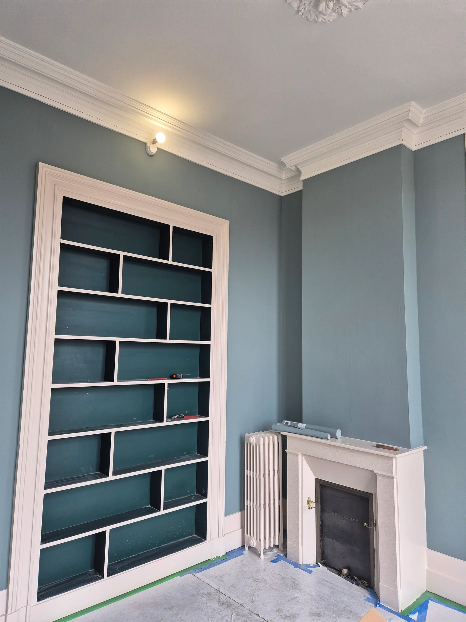 Peinture intérieure : bibliothèque encastrée et murs bleu-vert avec boiseries claires