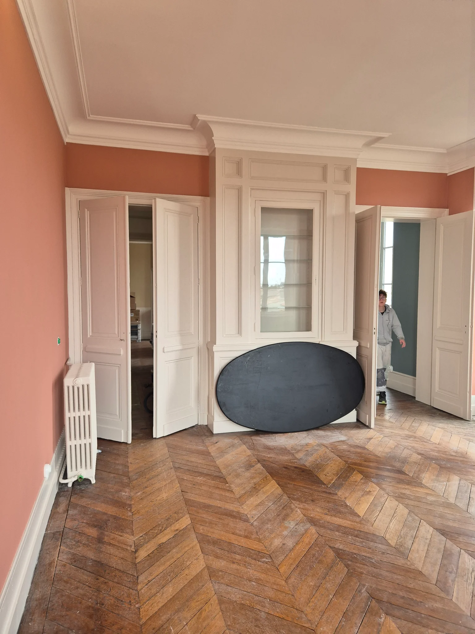 Salon aux murs terracotta et boiseries blanches sur parquet ancien