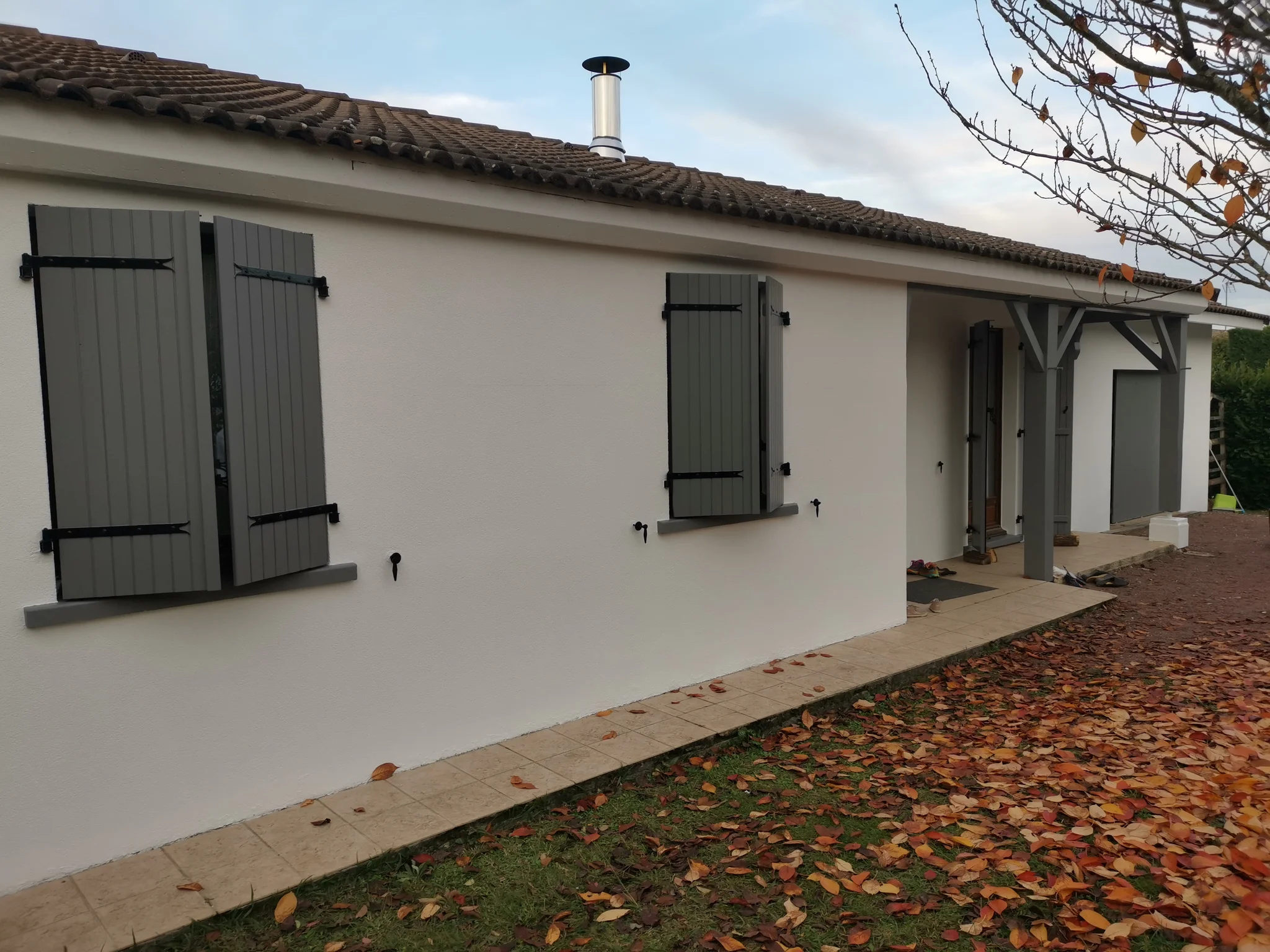 Façade de maison repeinte en blanc avec volets gris ardoise