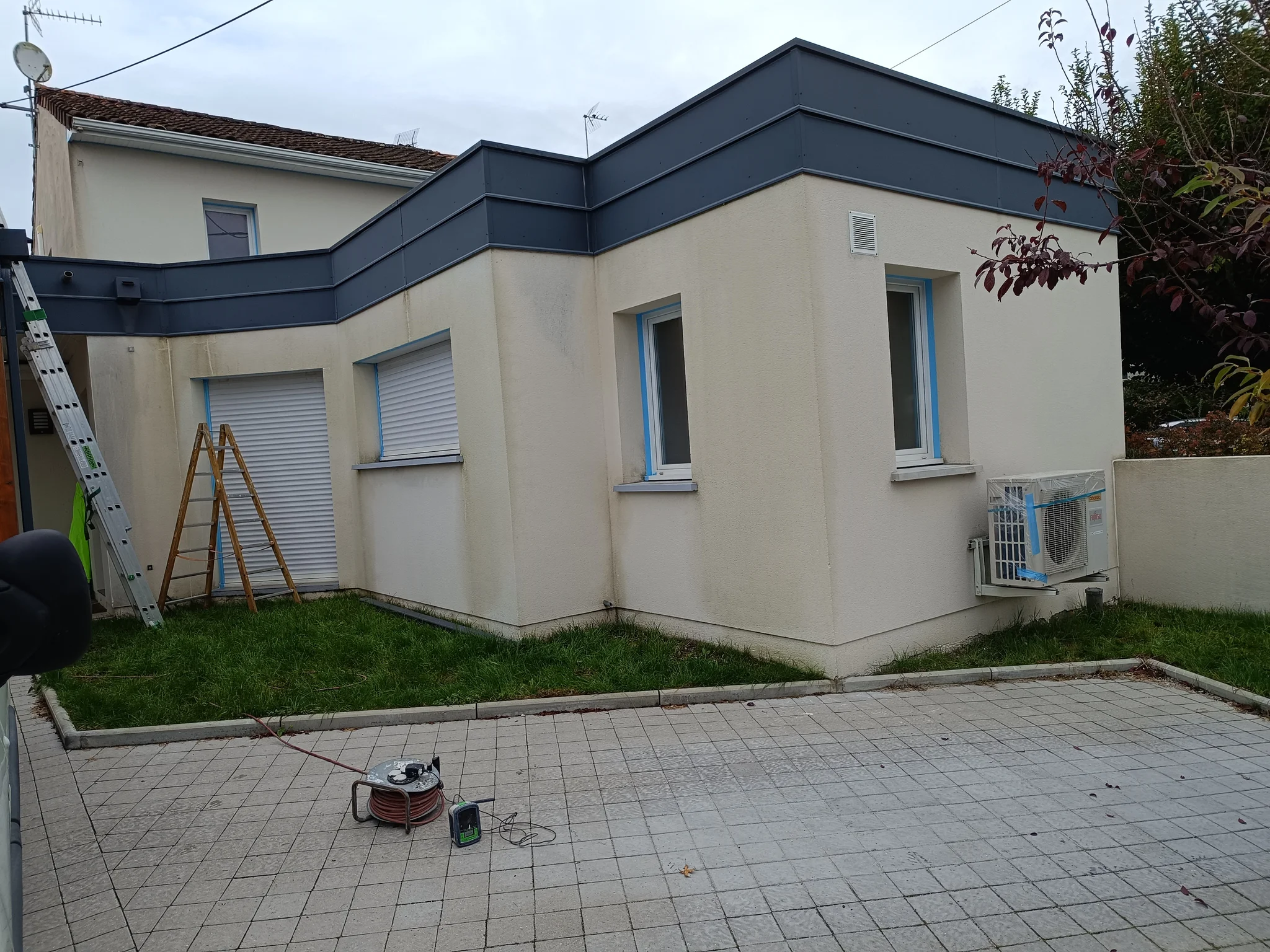 Façade de maison repeinte en ton crème avec bandeau gris anthracite